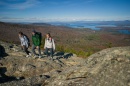 Three young people on rocky mountaintop with lake in background