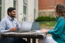 Two students working on laptops on campus