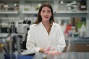Woman in a white lab coat standing in a lab setting