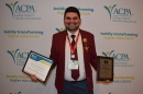 Man holding two awards in front of a white backdrop