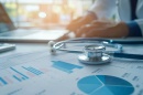A stethoscope lies on top of a sheet of graphs and charts