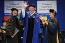 A man waves from the stage as he receives an honorary stole