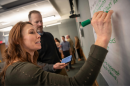 Woman writing at a whiteboard at a Paul College Executive Education course.