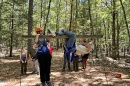 Two students in helmets and harnesses begin climbing up a ropes course