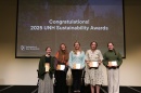 Five female students hold awards on a stage