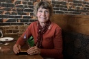 Karla Armenti sits in a restaurant booth holding an award and smiling