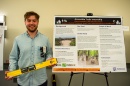Male student standing next to a poster for a presentation