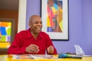 Man in a red shirt smiles while sitting at a table