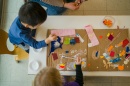 Shot from above, young child plays at a table of building blocks