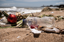 plastic trash laying on the sand near a beach