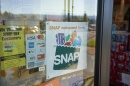 A window of a retail store displays a SNAP welcomed here sign