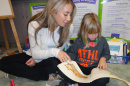 College student reading to younger student in literacy center