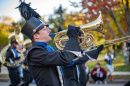 A student playing a horn in the UNH Homecoming Parade 