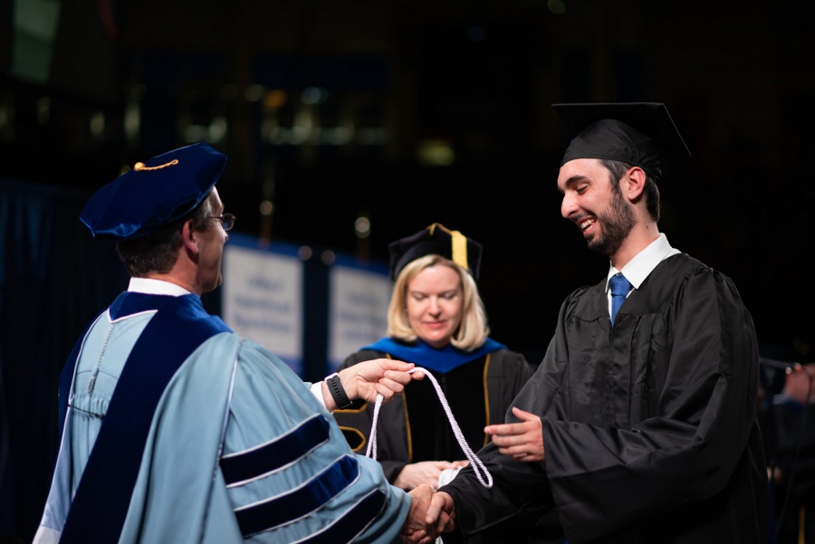 A UNH student receives their cord