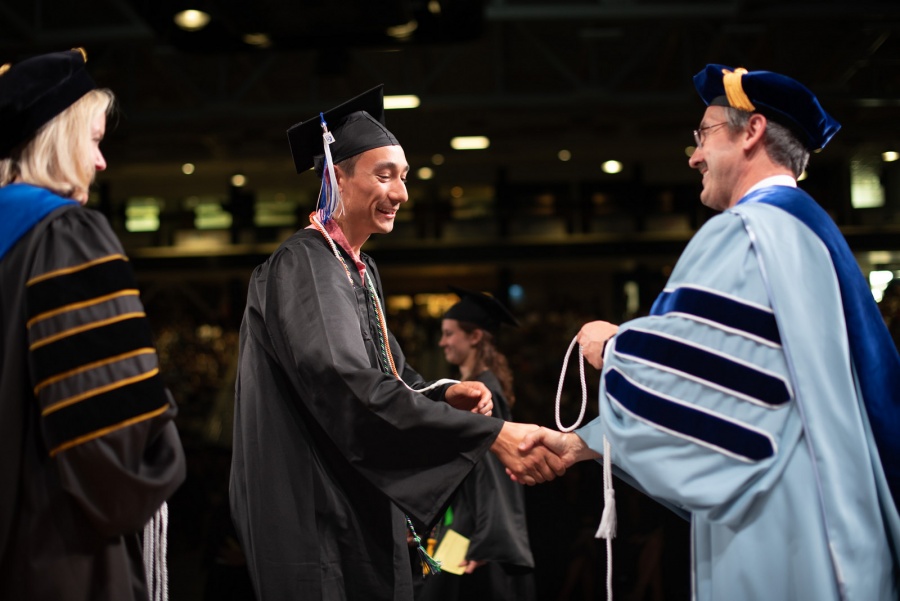 A UNH student receives their cord
