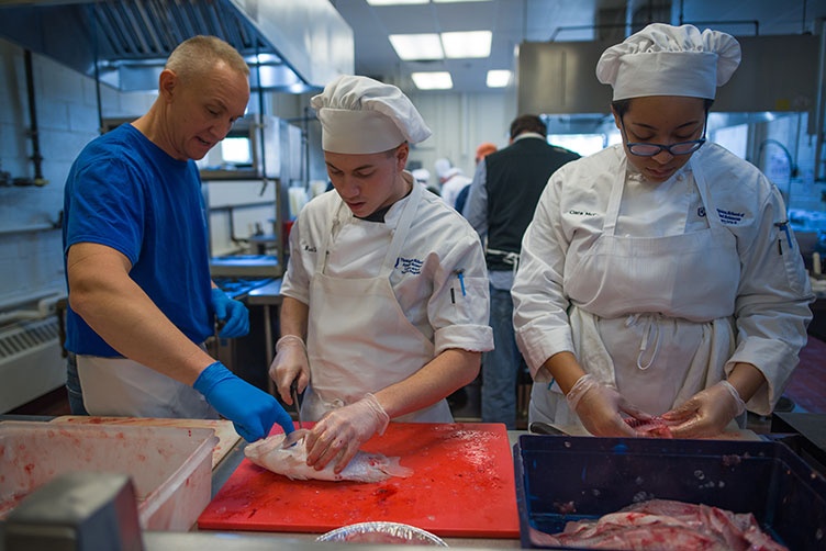 Brad LaMonica and Ciara McCarter from UNH’s Thompson School of Applied Science Culinary Arts & Nutrition program get a filet lesson from Rich Pettigrew, owner of Seaport Fish in Rye, N.H.