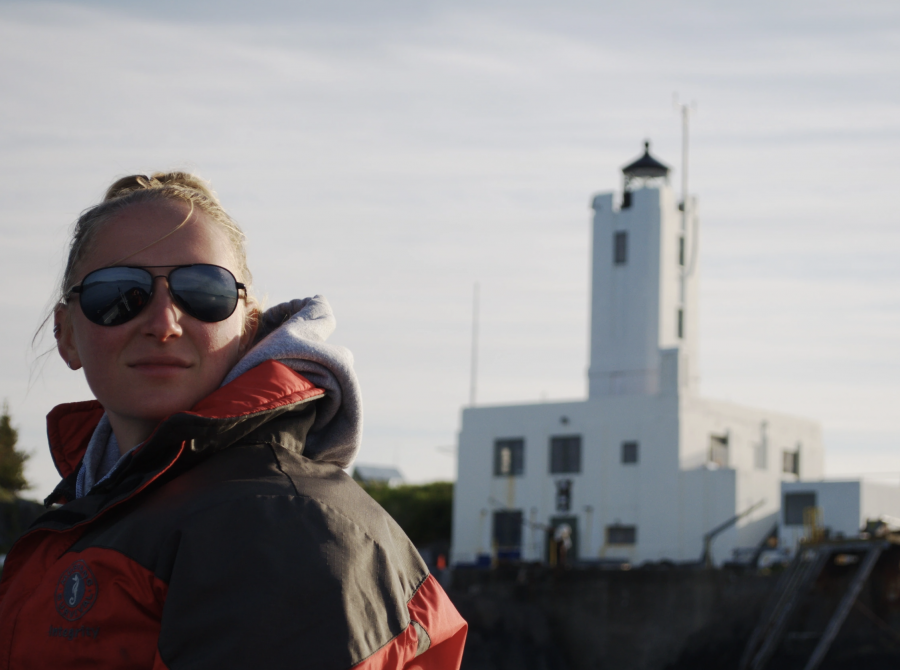 A photo of bioacoustics researcher Michelle Fournet with the Five Finger Lighthouse in the background