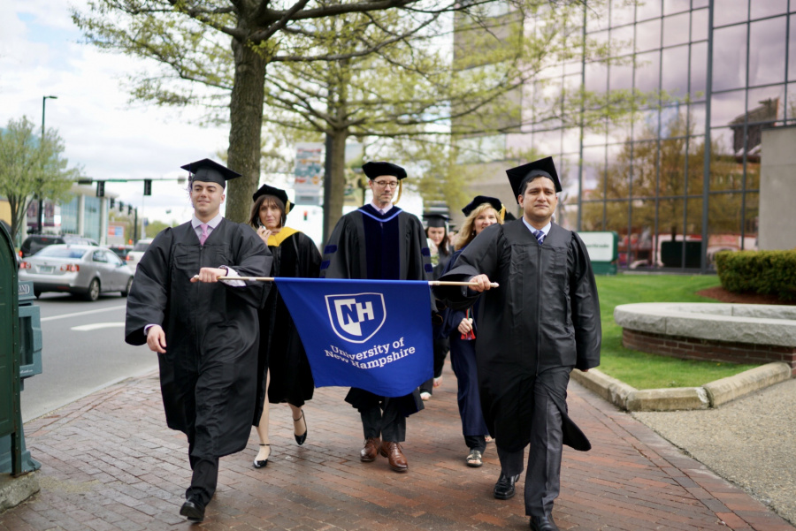 UNH Manchester Commencement participants walking with banner