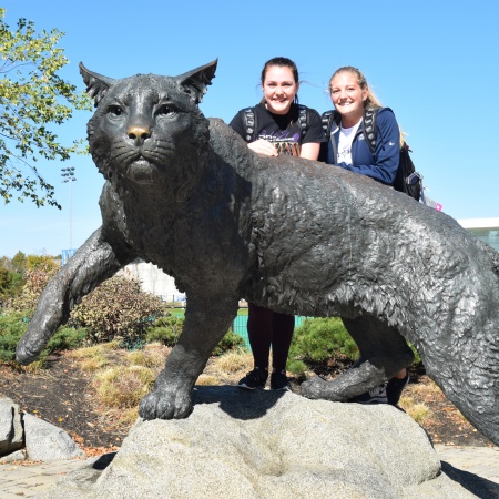 Two members of the UNH gymnastics team climbed atop the wildcat for a photo