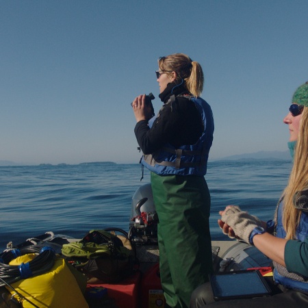 Michelle Fournet (right) and a fellow researcher looking for marine life during a research expedition in Alaska.