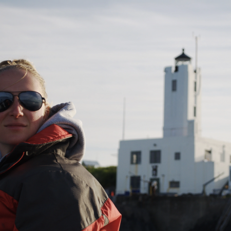 A photo of bioacoustics researcher Michelle Fournet with the Five Finger Lighthouse in the background