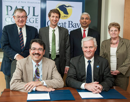 Great Bay Community College President Wildolfo Arvelo, seated from left, and University of New Hampshire President Mark Huddleston, celebrate the signing of an articulation agreement between the two institutions Wednesday, June 5, 2013. Pictured behind them, from left to right, are Paul Holloway, chairman of the Community College System of New Hampshire Board of Trustees; Ross Gittell, chancellor of  the Community College System of New Hampshire; Venky Venkatachalam, associate dean at the UNH Paul College; and Diane King, dean of academic affairs  at Great Bay Community College.