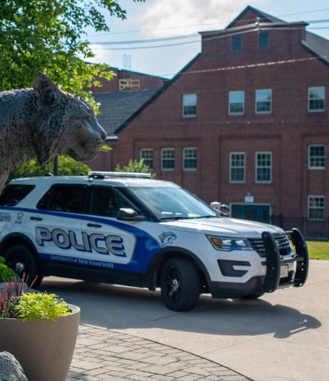 UNH Police Department vehicle and Wildcat Statue