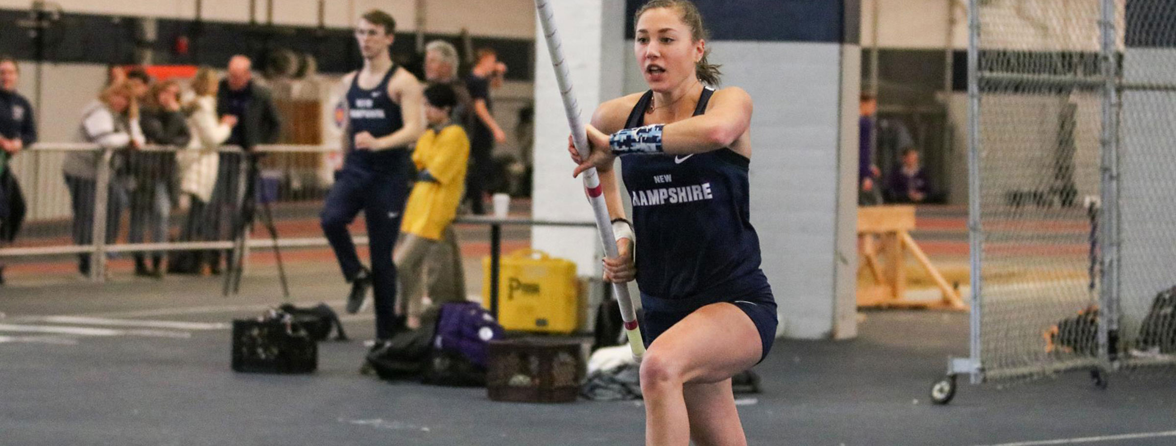 UNH indoor track female student running down track pole vault event
