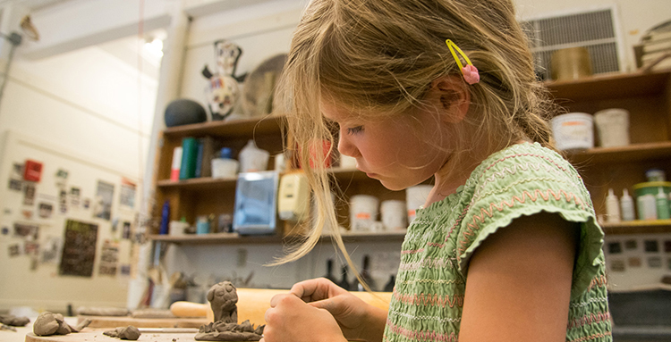 young female at UNH art camp working with clay