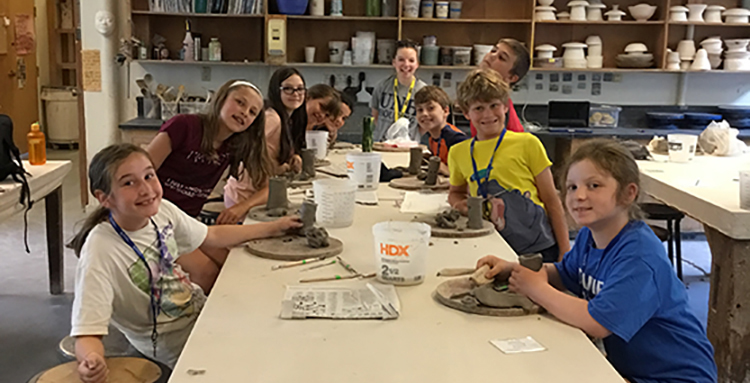Young art campers surrounding art table in UNH Art Camp studio