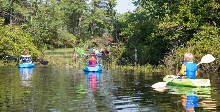 Kids kayaking on lake as part of UNH youth kayaking camp
